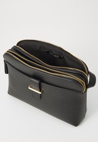 Sac en cuir noir texturé avec des zippers dorées, comportant deux compartiments et une forme rectangulaire. Les détails incluent un accent en métal doré.