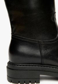 Schwarze Leder-Ankle Boots mit glatter Textur, abgerundetem Fuß, Gummisohle mit Profil und dezenten Nähten entlang der Nähte.