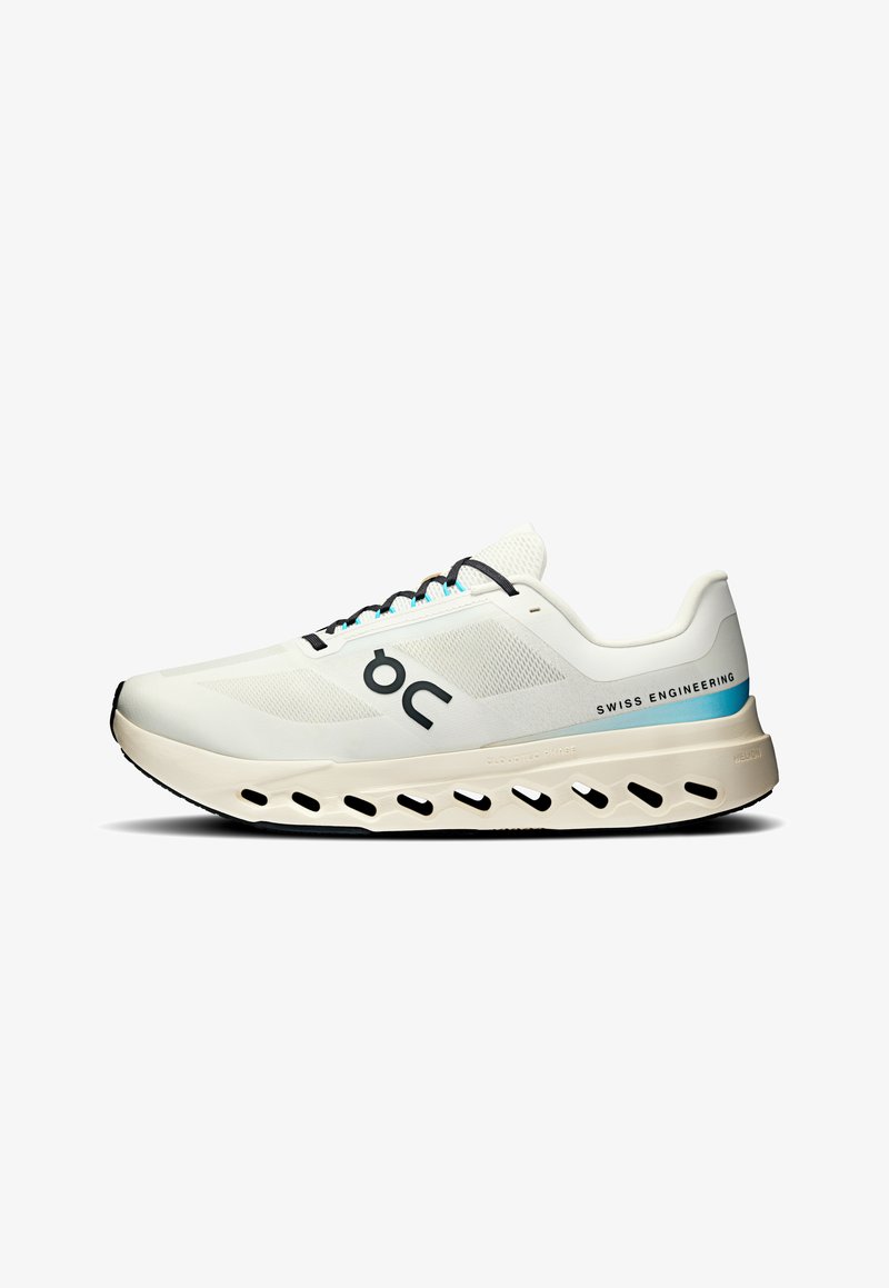 Zapatilla de running blanca con parte superior de malla transpirable, acentos en negro y turquesa, suela acolchada y diseño distintivo de cortes para ventilación.