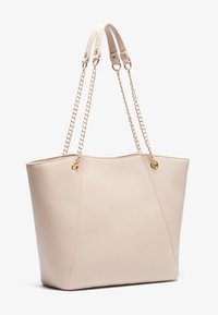 Beige tote bag made of textured synthetic material. Features gold chain straps and a sleek, angular design with subtle stitching details.
