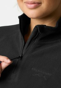 Zwarte fleece pullover met hoge kraag, halve rits en geborduurd "SWEDEMOUNT" logo. Soepele textuur en verstelbare koord.