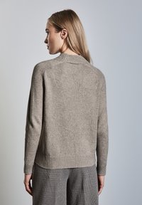 Licht taupe gebreide trui met een geribbelde ronde hals en zoom. Zachte textuur en casual pasvorm, met raglanmouwen en een naadloze achterkant.