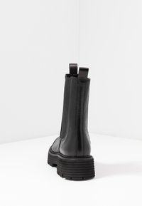 Schwarze Knöchelstiefel aus glattem Leder mit elastischen seitlichen Einsätzen und Zuglaschen. Robuste Textursohle mit ausgeprägten Rillen.