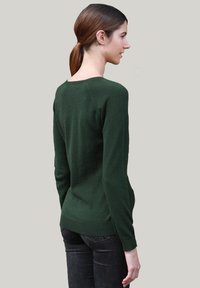 Pull en laine vert à manches longues, avec des poignets et un ourlet côtelés, ainsi qu'un col rond. Texture lisse et design ajusté.