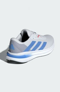 Chaussure de sport grise en matériau mesh, avec des accents bleus et un design à trois rayures, dotée d'une surface texturée et d'une semelle Cloudfoam.