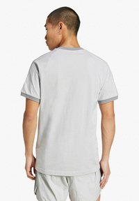 T-shirt grigio chiaro a maniche corte con scollatura rotonda e rilievo grigio a contrasto sulle maniche. Il tessuto sembra morbido con una vestibilità ampia.