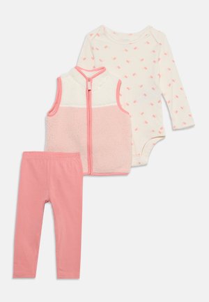 Leggings bébé rose doux, un gilet polaire blanc et rose zippé, et un body blanc manches longues avec un petit motif de feuilles roses.