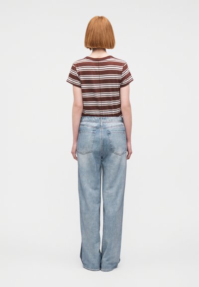 Ριγέ καφέ κοντομάνικη μπλούζα, συνδυασμένη με ανοιχτού μπλε ευρύχωρα τζιν. Η εμφάνιση χαρακτηρίζεται από casual σχέδια και άνετη εφαρμογή.