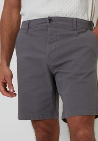 Shorts gris avec une fermeture à bouton, deux poches avant et des détails de couture subtils. Le tissu semble léger et à texture lisse.