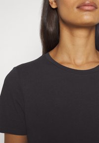 Donkergrijze katoenen T-shirt met een ronde halslijn en korte mouwen, met een gladde textuur en minimale ontwerpelementen.