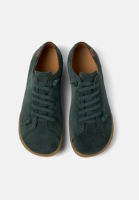 Sneakers in suede verde con punta tonda, lacci piatti e suola in gomma. Presentano cuciture laterali e un motivo testurizzato sulla tomaia.