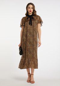 Rochie maxi cu imprimeu leopard dintr-un material transparent și texturat. Prezintă mâneci scurte învolburate și un detaliu cu funda neagră la gât. Bază evazată în partea de jos.