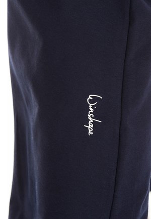 Námorné joggers s mäkkým bavlněným materiálom, úzkym strihom a bielym logom na ľavom stehne. Hladká textura bez vzorov.