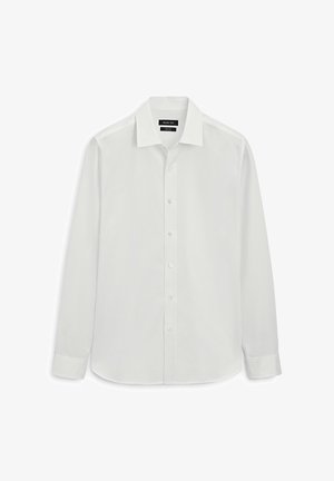 Chemise blanche à manches longues boutonnée, col pointu et poignets, présentée à plat sur fond blanc.