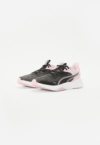 Baskets de sport noires et roses avec une tige texturée, semelle intermédiaire blanche, semelle extérieure rose et logo Puma prominent sur le côté.