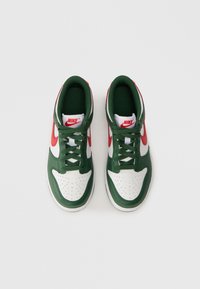 Sapatilhas altas com um cabedal em couro branco, detalhes em couro verde, swoosh vermelho da Nike e forro em tecido verde texturizado. Design de bico perfurado.