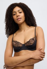 Μαύρο σουτιέν με ποτηράκια σε σχέδιο λεοπάρ, διακοσμημένα με βολάν, ρυθμιζόμενες τιράντες και λείο ύφασμα για κομψό σχεδι ασμό.