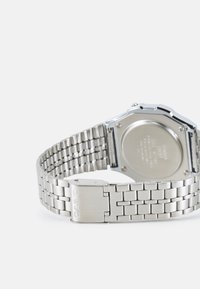 Montre-bracelet Casio argentée avec un bracelet en métal, un boîtier octogonal et une boucle déployante. Texture lisse avec un logo gravé sur la boucle.