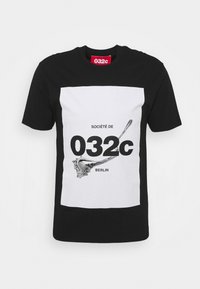 T-shirt en coton noir présentant un grand motif rectangulaire blanc avec l'inscription « SOCIÉTÉ DE 032c BERLIN » et un design éclaboussé argenté au centre.