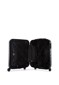 Black hard-shell suitcase with zipper closure, interior straps, and zip pocket. Textured exterior with horizontal ridges. Four wheels for mobility.