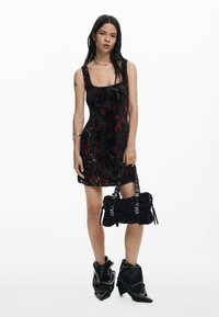 Mustast ja punasest mustriga minikleidi ruudukujulise dekolteega, koos musta volditud käekoti ja mustade paksu tallaga pahkluu saabastega.