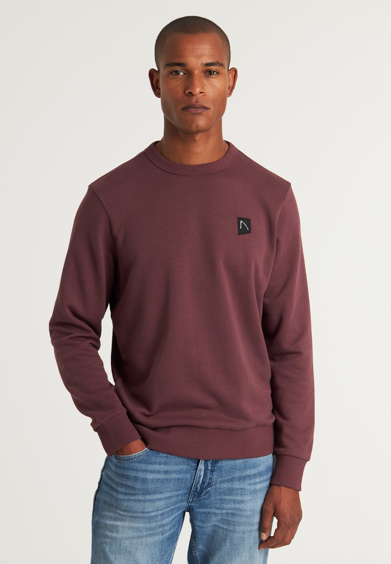 Sudadera burdeos con cuello redondo, puños y bajo acanalados. Presenta un pequeño parche de logo negro en el lado izquierdo del pecho. Material de mezcla de algodón.