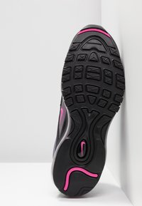 Semelle de basket noire avec un motif de bande de roulement profond, des accents roses et un petit logo Nike swoosh rose près du talon.