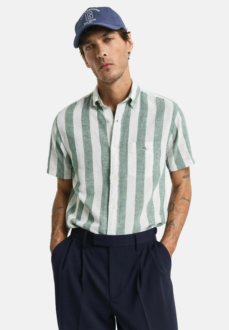 Camisa de manga corta con botones, en tejido con rayas verticales verdes y blancas, hecha de un material texturizado, que cuenta con un bolsillo en el pecho y un corte casual.