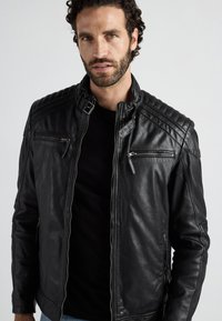 Schwarze Leder-Bikerjacke mit einem Reißverschluss, zwei vorderen Reißverschlusstaschen, gesteppten Schulterdetails und einem hohen Kragendesign.