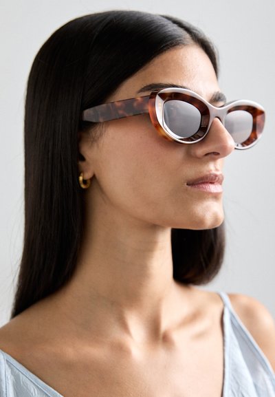 Gafas de sol de ojo de gato hechas de plástico con un patrón de carey y un acabado brillante, que cuentan con montura ancha y redondeada y lentes espejadas.
