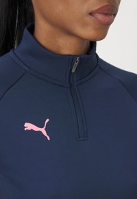 Námornícky zipsový športový top s vysokým golierom, na ľavej strane hrudníka s ružovým logom Puma a ľahkým, hladkým povrchom.