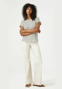 Gestreepte blouse met korte mouwen en ruffles, gecombineerd met crèmekleurige wijde broek. Heeft een losse pasvorm, zachte stof en platte sandalen.