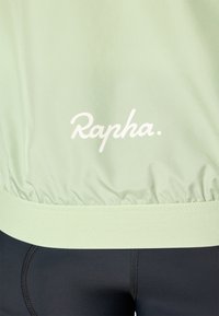 Hellgrüne Radjacke mit elastischem Bund, versehen mit einem weißen "Rapha."-Logo. Glatte Textur und leichtes Material, entworfen für optimale Leistung.