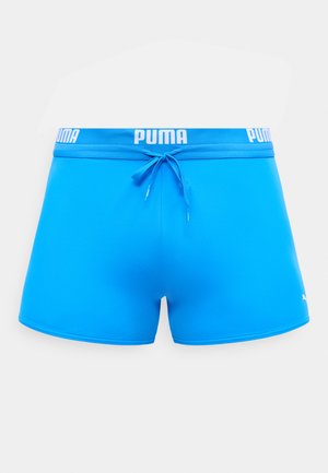 Lyseblå Puma badeshorts med snor i midjen og hvit Puma-logo på midjebåndet og nederst på høyre ben.