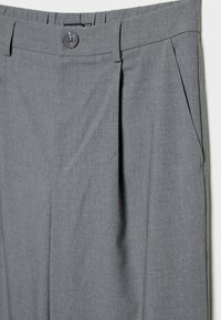 Pantalon gris sur mesure avec une texture tissée lisse, plis devant et fermeture à un seul bouton. Coupe droite flatteuse.