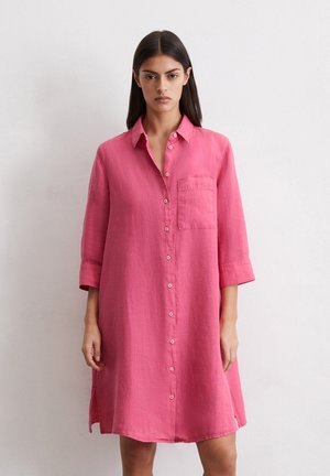 Rosa Leinenhemdkleid mit durchgehender Knopfleiste, Kragen, Dreiviertelärmeln und einer Brusttasche. Weicher Textur, lockerer Schnitt.