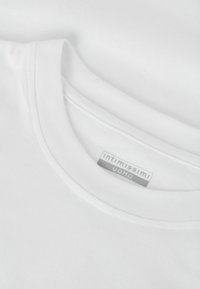 Bílý bavlněný tričko s kulatým výstřihem, jemná textura a viditelný značkový štítek: "intimissimi" a "UOMO." Jednoduchý design.