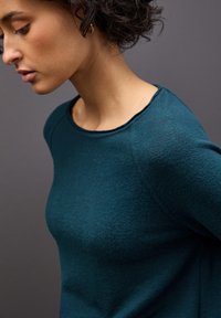 Tiefgrüner gestrickter Pullover mit Rundhalsausschnitt und strukturiertem Stoff, der eine taillierte Silhouette und leicht raglanärmel bietet.