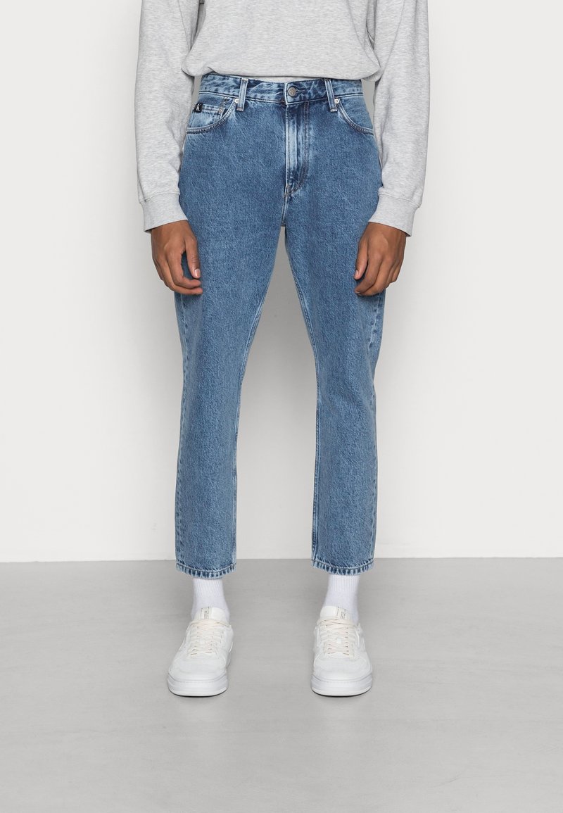 Jeans in denim blu chiaro con una vestibilità rilassata, vita alta e gambe dritte. Presentano cinque tasche e una leggera scoloritura. Indossati con sneaker bianche.