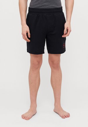 Black shorts made of soft fabric, featuring an elastic waistband, side pockets, and a small red logo detail on the left thigh.