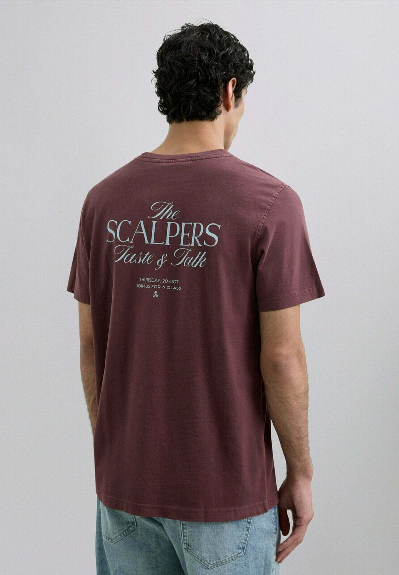 Camiseta de color burdeos de manga corta, textura suave, con texto blanco en la parte posterior: "The SCALPERS Taste & Talk" y detalles del evento.