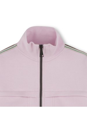 Veste zippée rose clair avec un col haut, tissu texturé, et détails en bandes vertes et noires le long des épaules. Poches avant incluses.