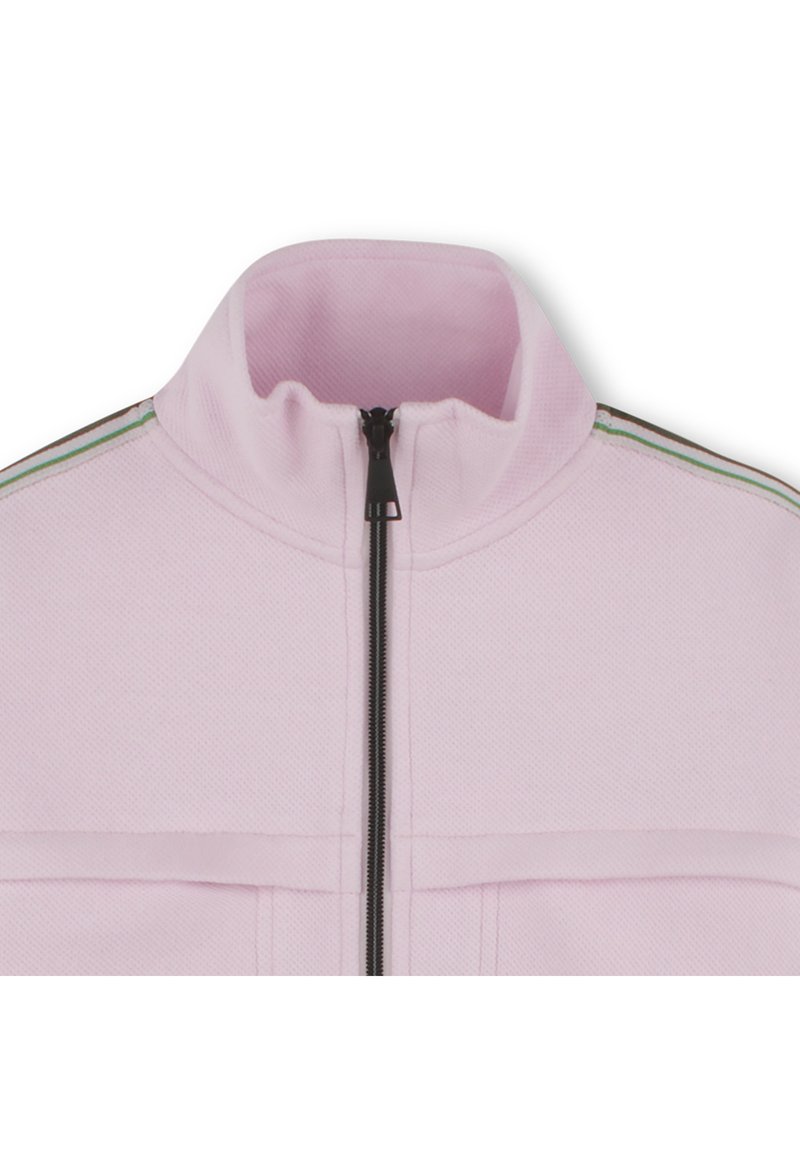 Lichtroze zip-up jack met hoge kraag, gestructureerde stof en groene en zwarte strepen langs de schouders. Voorzakken inbegrepen.