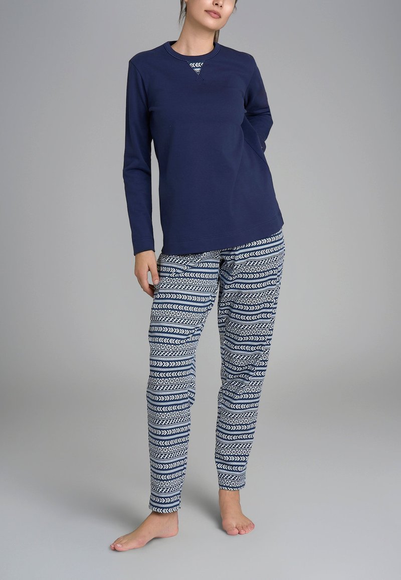 Maglietta a maniche lunghe blu navy con scollatura a girocollo abbinata a pantaloni del pigiama con motivo geometrico bianco su sfondo blu.