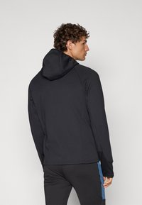 Giacca nera con cappuccio, dal materiale liscio e dal design aderente. Presenta un accento blu a contrasto sul lato e una vestibilità regolare.