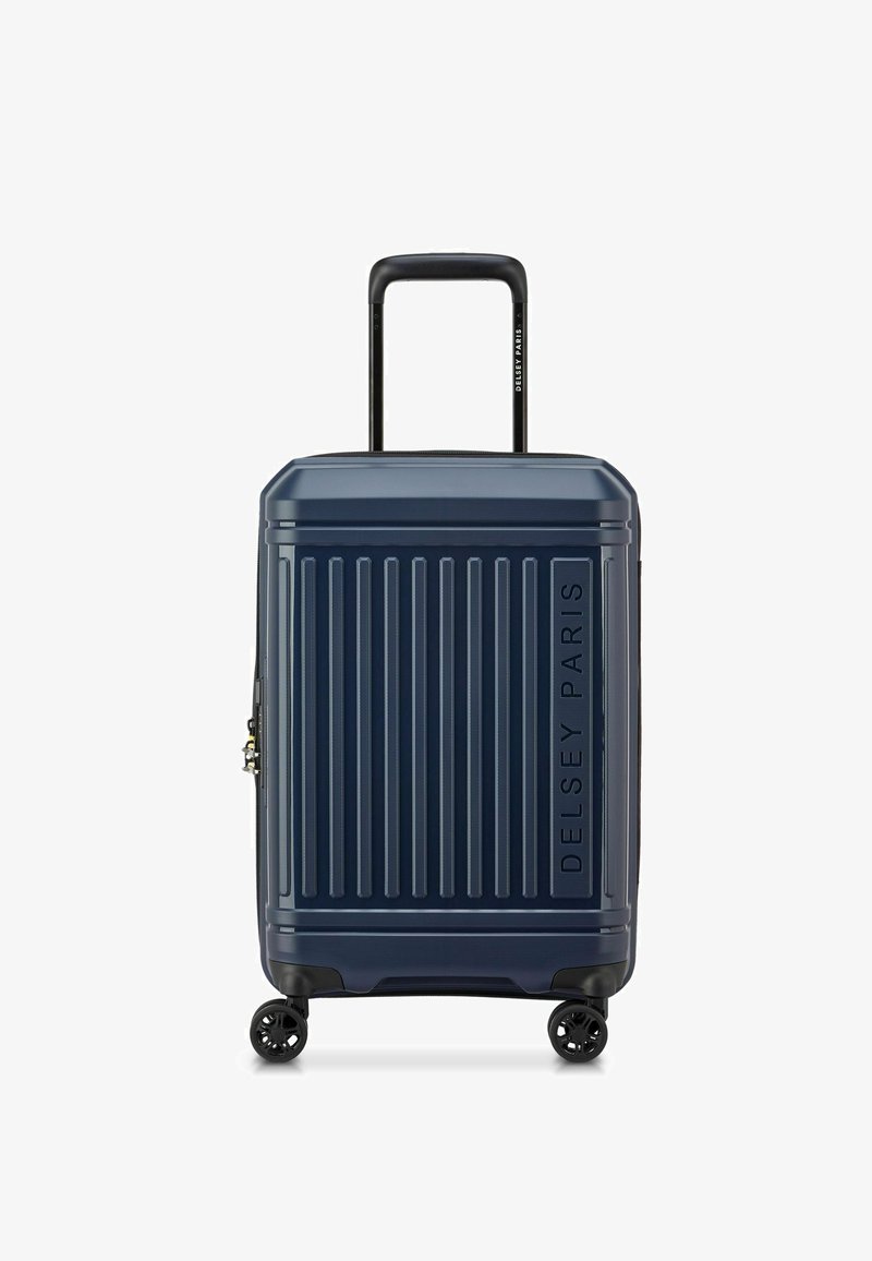 Maleta rígida de color navy con estrías verticales, un asa retráctil y cuatro ruedas negras. Presenta un logo de la marca en un lateral.