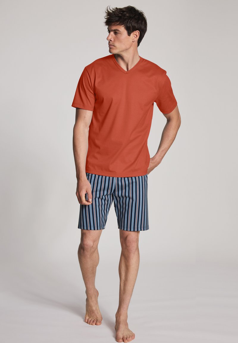 Rode v-hals t-shirt en blauwe gestreepte short. Het shirt heeft korte mouwen; de short heeft verticale strepen in verschillende tinten blauw en wit.