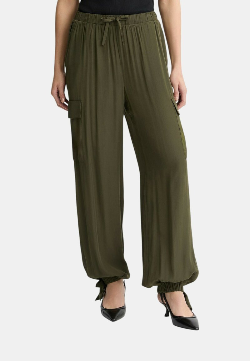 Pantalones de pierna ancha en verde oliva con cintura elástica y puños atados. Presenta bolsillos laterales tipo cargo y una textura fluida. Combina con tacones negros.