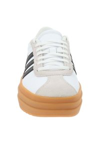 Białe sneakersy z szarymi zamszowymi akcentami, czarnymi paskami i teksturowaną gumową podeszwą. Sznurówki są białe, a buty mają zaokrąglony czubek.