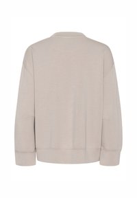 Sweat-shirt beige à manches longues avec col rond, épaules tombantes et coutures visibles à l'arrière et sur les manches.